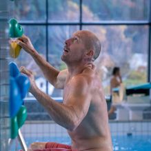 Mann klatrer i klatrevegg i bassenget
