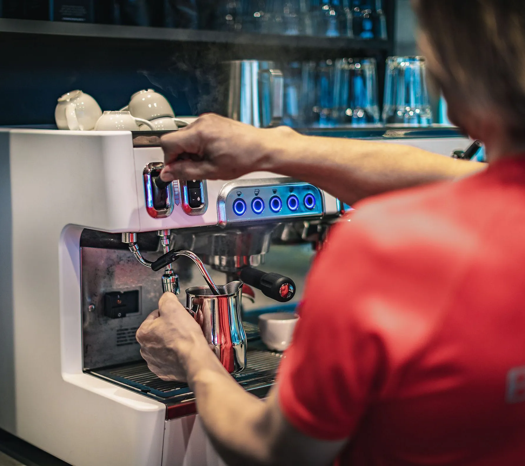 Mann steamer melk til kaffe i kafeén