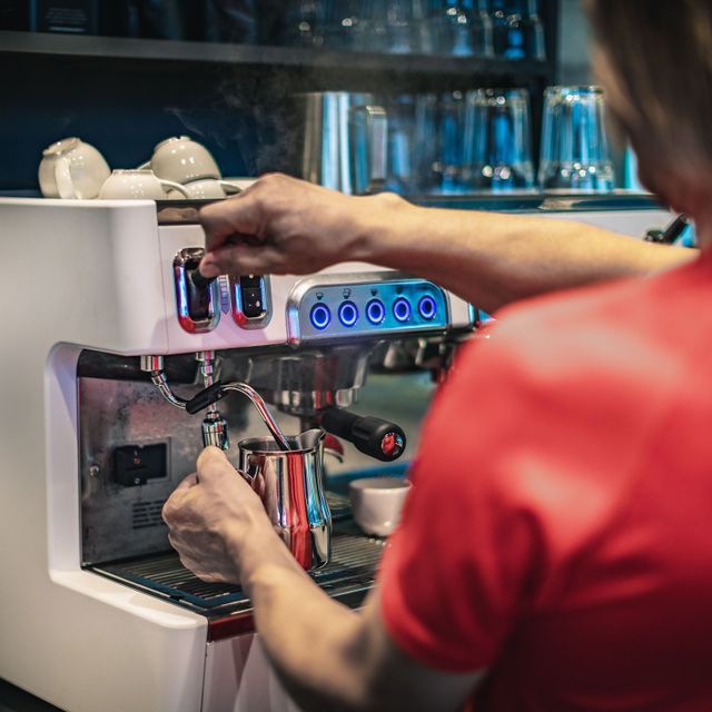 Mann steamer melk til kaffe i kafeén